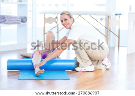 Trainer working with woman on exercise mat in medical office