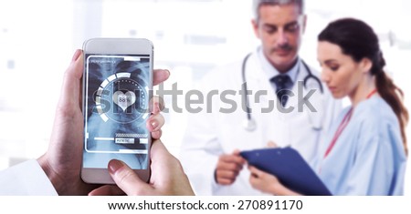 Hand holding smartphone against nurse and doctor looking a file