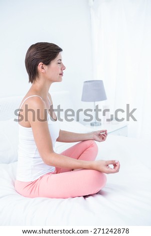 Peaceful woman doing yoga in her bed at home in the bedroom