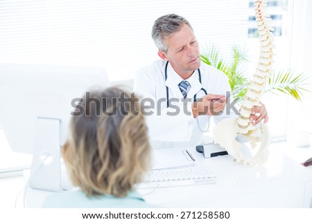 Doctor showing spine model to his patient in medical office