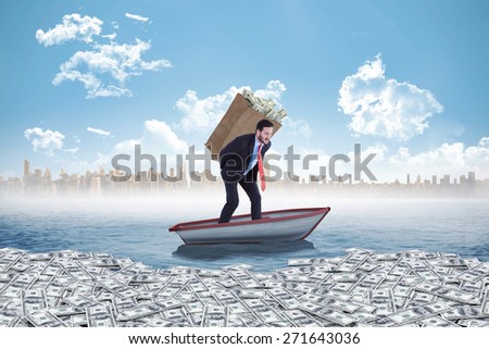 Businessman carrying bag of dollars against small boat in the sea with city on horizon