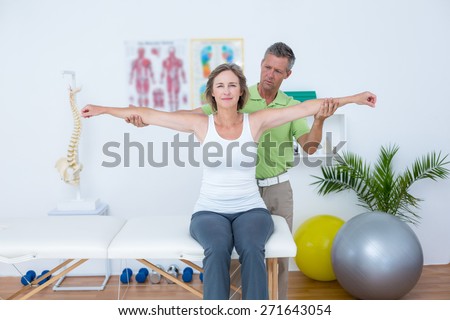 Doctor stretching his patients arms in medical office