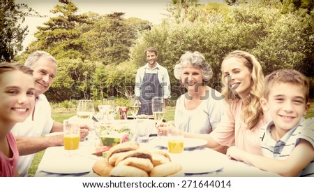 Happy extended family waiting for barbecue being cooked by father smiling at camera