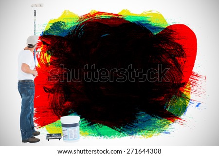 Man using paint roller on white background against red green black yellow and blue paint