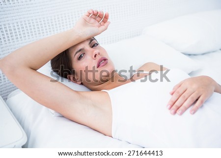 Pretty brunette suffering from head ache at home in the bedroom