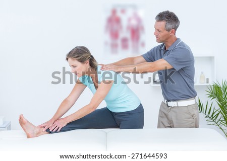 Physiotherapist helping his patient stretching in medical office