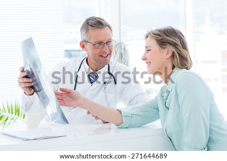 Doctor having conversation with his patient and holding xray in medical office