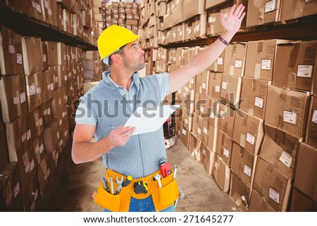 Male supervisor with hand raised holding clipboard against boxes in warehouse