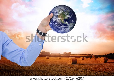 Businessman holding hand out in presentation against countryside scene