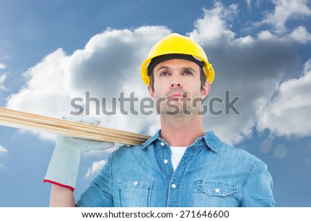 Worker carrying wooden planks against cloudy sky