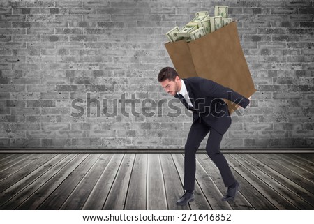 Businessman carrying something heavy with his back and hands against grey room
