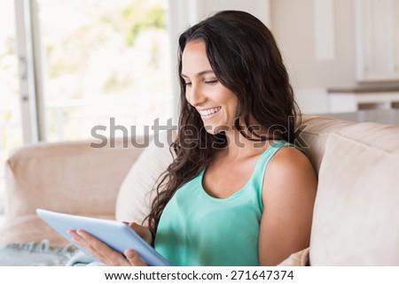 Pretty brunette using tablet pc on the couch at home in the living room