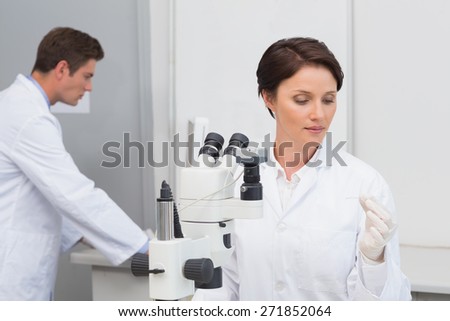 Scientists working with microscope and computer in laboratory