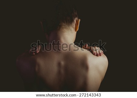 Nude woman with a shoulder injury on black background