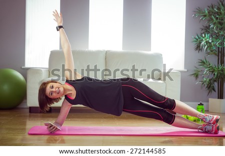 Fit woman doing side plank at home in the living-room
