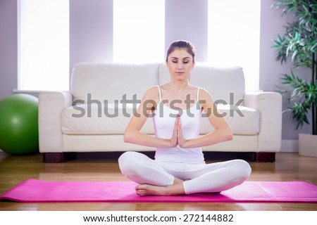 Fit woman doing yoga on mat at home in the living room