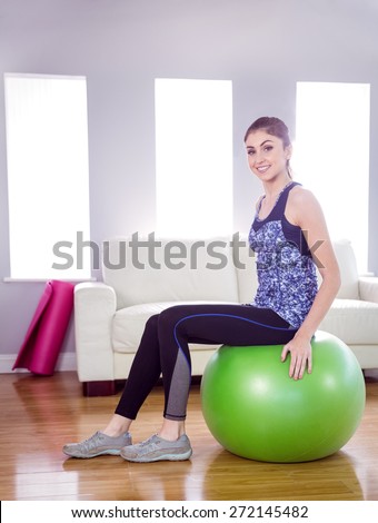 Fit woman sitting on exercise ball at home in the living room