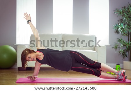Fit woman doing side plank at home in the living-room