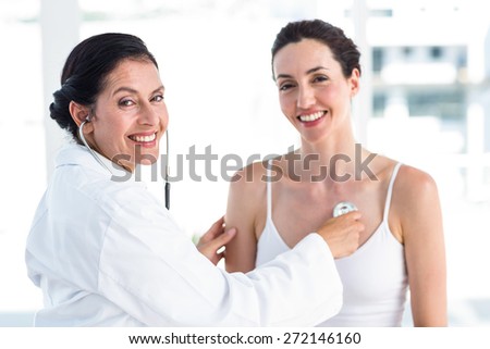 Doctor listening to patients chest with stethoscope in medical office