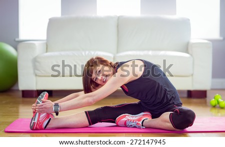 Fit woman stretching on exercise mat at home in the living-room