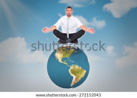 Businessman meditating in lotus pose against blue sky