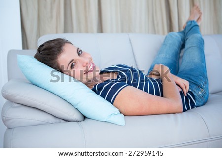 Beautiful woman lying on couch smiling at camera in the living room