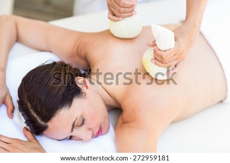 Brunette having massage with herbal compresses in the health spa
