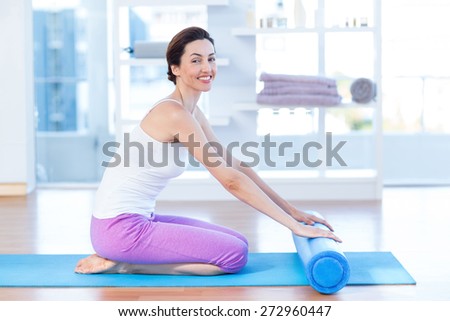 Smiling woman sitting on exercise mat in medical office
