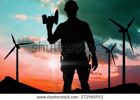 Confident male repairman holding drill machine against blue and pink sky