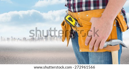 Close-up of male repairman wearing tool belt against city on the horizon