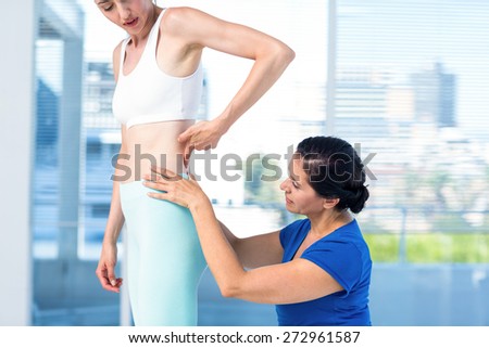 Therapist examining her patients back in exercise room