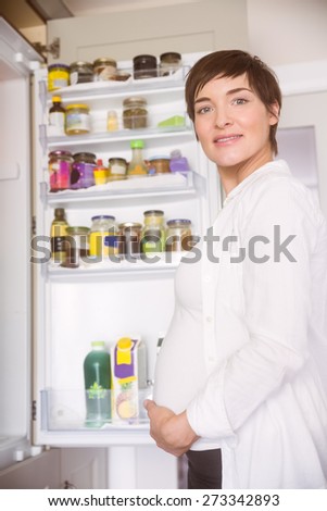 Pregnant woman opening the fridge at home in the kitchen