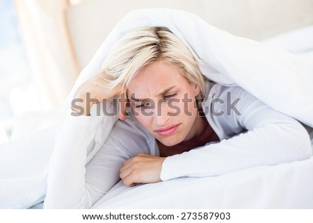 Sad blonde woman lying on the bed in her bedroom