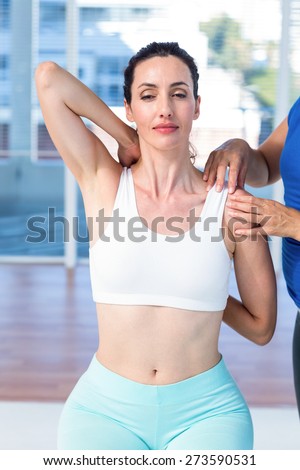 Woman stretching her arm with her therapist in medical office