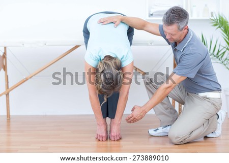 Physiotherapist helping his patient stretching in medical office