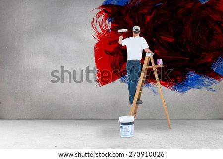 Man on ladder painting with roller against grey room