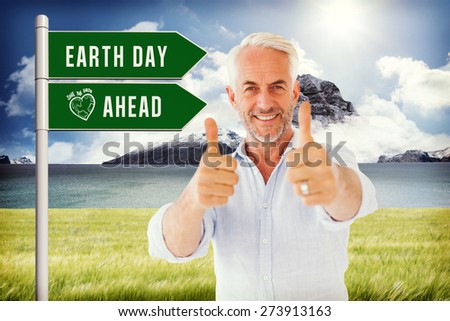 Smiling man showing thumbs up to camera against scenic backdrop