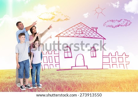 Family of four pointing at copy space against blue sky over green field