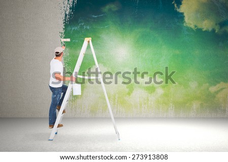 Handyman climbing ladder while using paint roller against painted sky