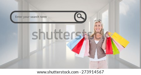 Happy blonde holding shopping bags against bright white hall with windows