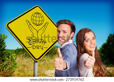 Happy young couple gesturing thumbs up against mountain trail
