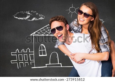 Smiling young man carrying woman against black wall
