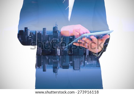 Businessman touching his tablet pc against mirror image of city skyline