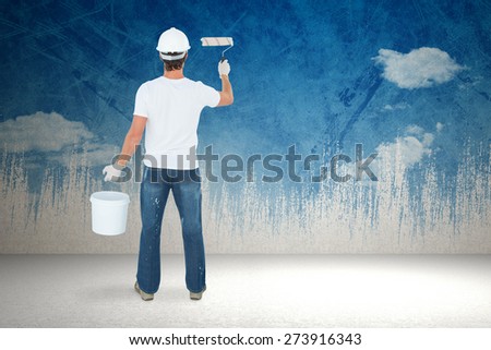 Rear view of man using paint roller against painted sky
