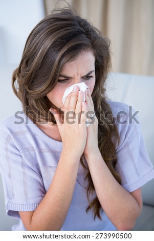 Sick woman blowing her nose at home in the living room