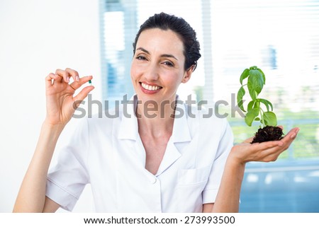 Scientist holding basil plant and pill in laboratory