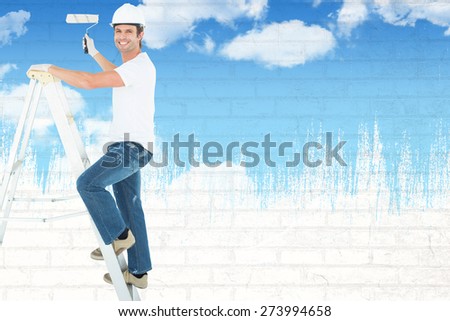 Portrait of man on ladder painting with roller against blue sky