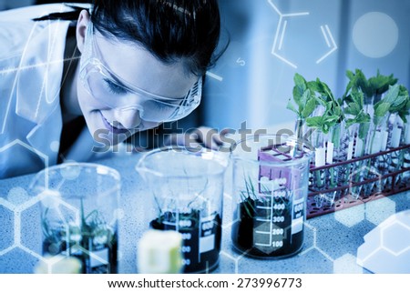 Science graphic against female researcher looking at young plants at lab