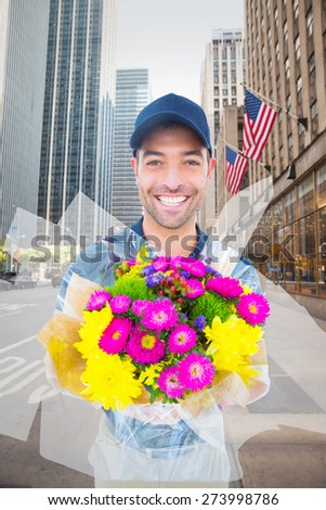 Happy delivery man holding bouquet against new york street