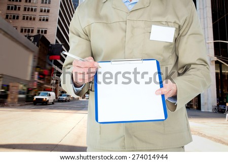 Delivery man showing blank paper on clipboard against new york street
